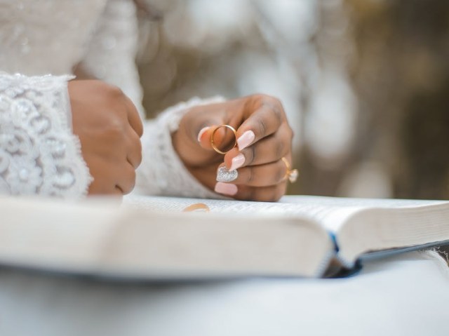 crop bride holding ring and reading wedding vow