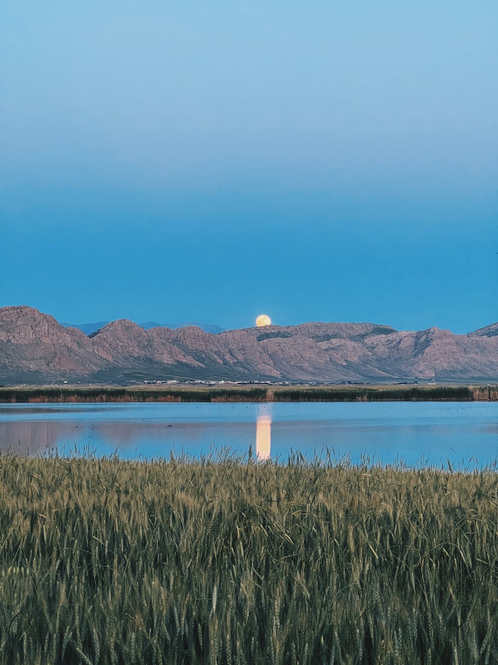 mountain landscape and the moon reflecting in a lake